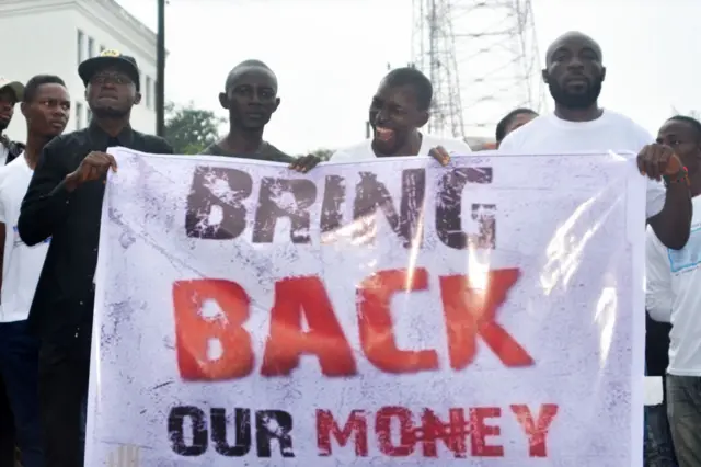 Liberians hold a banner during a demonstration over the disappearance of newly printed bills on 24 September 2018, in the capital, Monrovia.