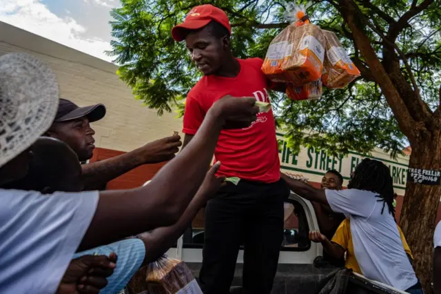 People jostle for a chance to buy a loaf of bread from a vendor at a market in Bulawayo on January 16, 2019, as shops and offices remain closed for business in the central business district following violent protests in the country triggered by a sharp, sudden rise in fuel prices.