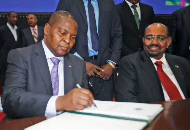 Central African president Faustin-Archange Touadera (L) signs a peace deal next to Sudanese President Omar al-Bashir in Khartoum on February 05, 2019.