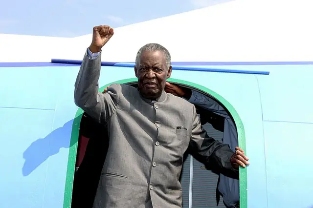 Michael Sata gestures upon arrival at Solwezi airport before addressing supporters at an election campaign meeting on September 10, 2014