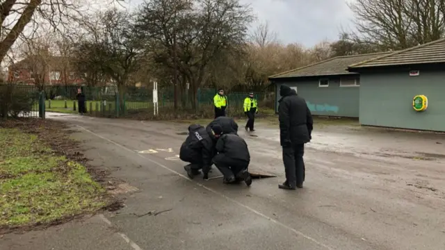 Police lifting manhole covers