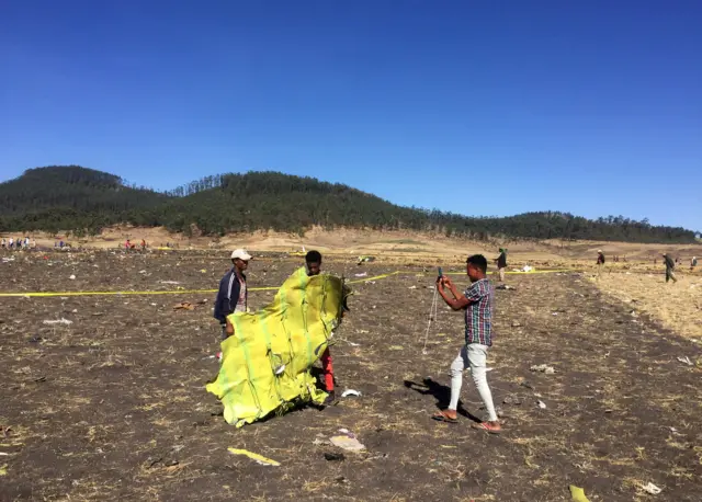 A civilian takes a photograph of the wreckage at the scene plane crash, near the town of Bishoftu, southeast of Addis Ababa