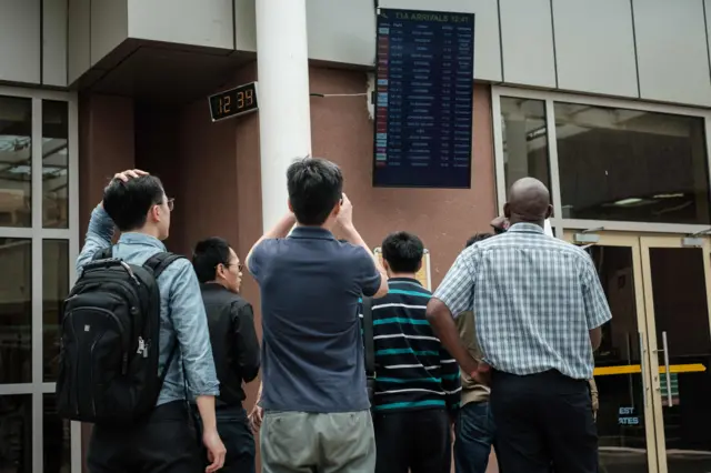 A Chinese group look at the arrival flight schedule for their colleagues who were allegedly onboard the plane that crashed at the Jomo Kenyatta International Airport in Nairobi, Kenya, on March 10, 2019