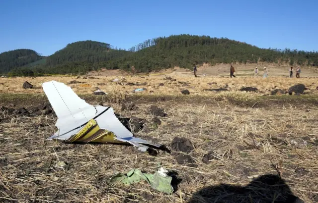 A piece of the fuselage of ET Flight 302 can be seen in the foreground as local residents collect debris at the scene where Ethiopian Airlines Flight 302 crashed in a wheat field just outside the town of Bishoftu, 62 kilometers southeast of Addis Ababa on March 10, 2019 in Addis Ababa, Ethiopia