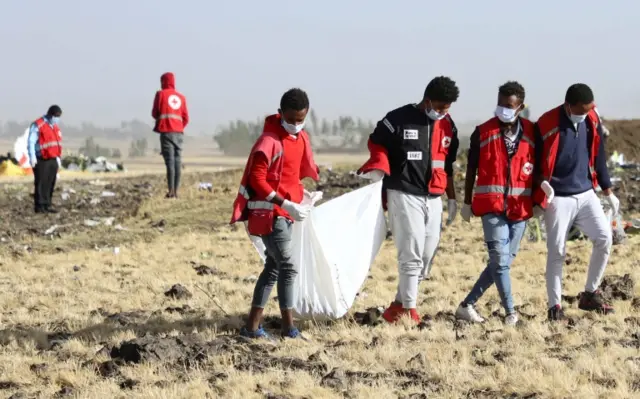 Members of the search and rescue team carry dismembered parts of passengers bodies at the scene of the Ethiopian Airlines Flight ET 302 plane crash