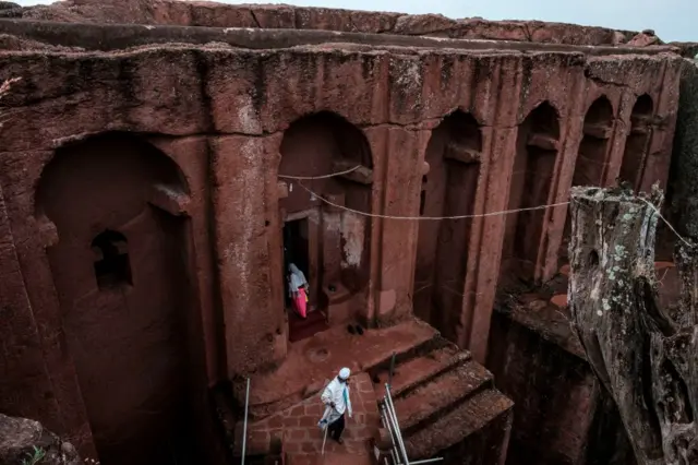 Ethiopian Orthodox devotees walk between the rock-hewn churchs of Saint Gabriel and Saint Raphael in Lalibela, Ethiopia, on March 7, 2019