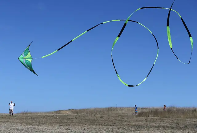 A man flies a kite with a long tail.