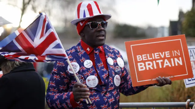 Pro-Brexit supporter Joseph Afrane waves the Union flag as he demonstrates outside the Houses of Parliament in London