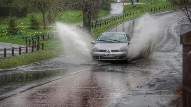 A car goes through water on a road in Birmingham