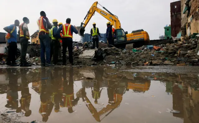 Rescuers work at the site of a collapsed building containing a school