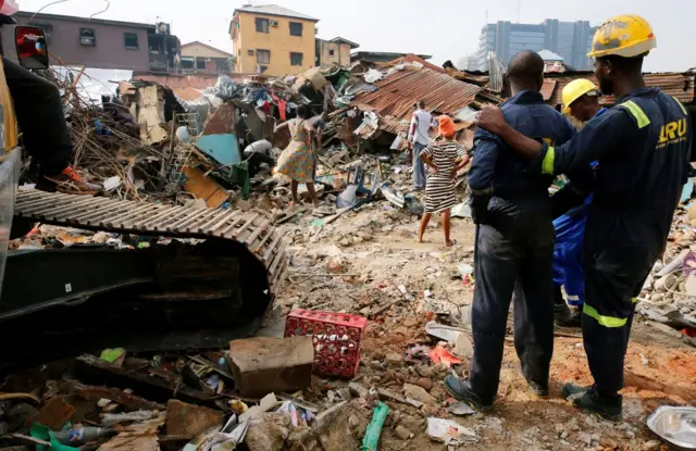 Rescuers are seen as people search for belongings at the site of a collapsed building