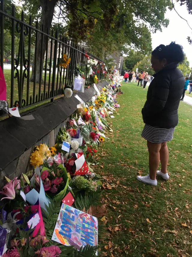 A woman looks at flowers and tributes at the memorial in Christchurch