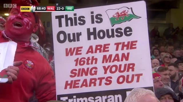 A Wales fan with a sign saying 'we are the 16th man sing your hearts out'