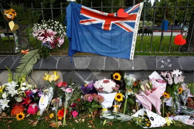 Flowers and a New Zealand national flag placed as tributes to victims of the mosque attacks near Linwood mosque in Christchurch, New Zealand