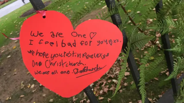 A heart-shaped sign with child's writing saying we are one, I feel bad for you, I hope you read in peace