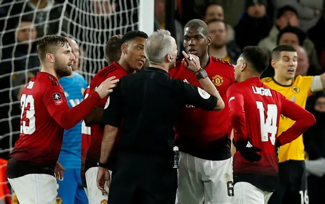 Manchester United players protest with referee Martin Atkinson