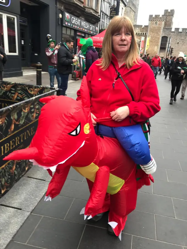 A woman in fancy dress that makes it look like she's riding a dragon