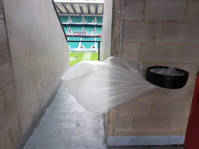 A bin bag blowing in the wind with the pitch behind