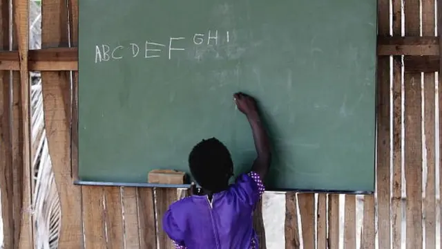 A schoolgirl writes on a blackboard with chalk