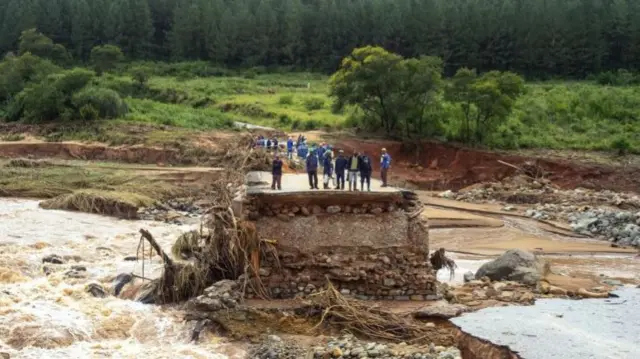 Timber company workers stand stranded on a damaged road on 18 March at Charter Estate, Chimanimani, eastern Zimbabwe, after the area was hit by Cyclone Idai.