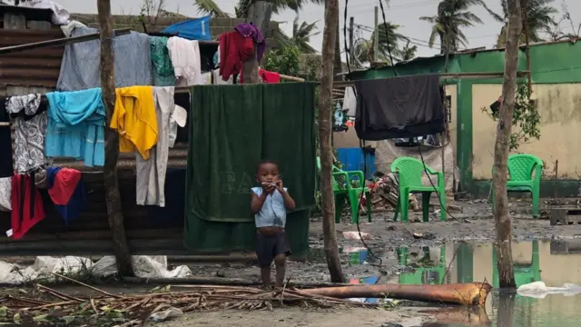 A young child stands by homes and encroaching floodwater, Beira, Mozambique