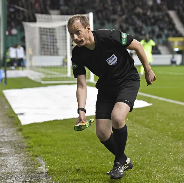 Referee Willie Collum removes a bottle thrown at Celtic winger Scott Sinclair