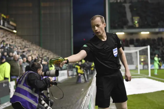 Referee Willie Collum removes a bottle thrown by someone in the home section at Easter Road