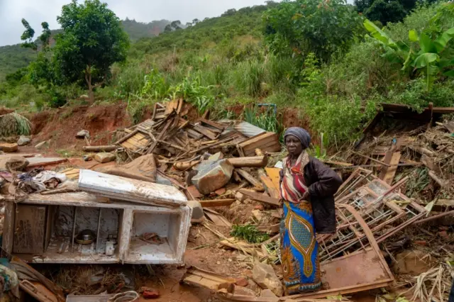 An elderly woman stands next to her destroyed belongings on March 19, 2019, after the area was hit by the Cyclone Idai.