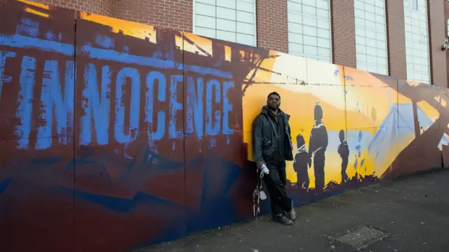 Mohammed Ali leaning against the painted wall