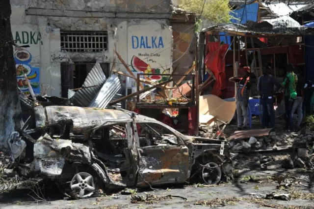 People look at the scene of a car bomb attack near a security checkpoint in the Somali capital, not far from the presidential palace in Mogadishu on March 7, 2019