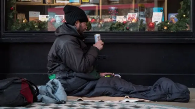 Homeless man drinking a can of beer