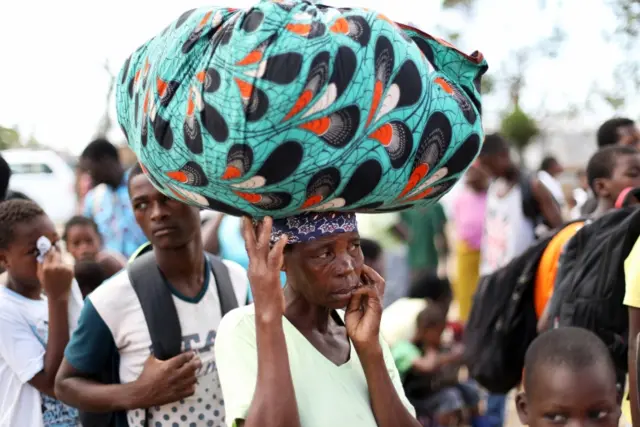 Evacuees from Buzi village carry their belongings as they arrive at the displacement center near the airport, after Cyclone Idai, in Beira, Mozambique, March 25, 2019