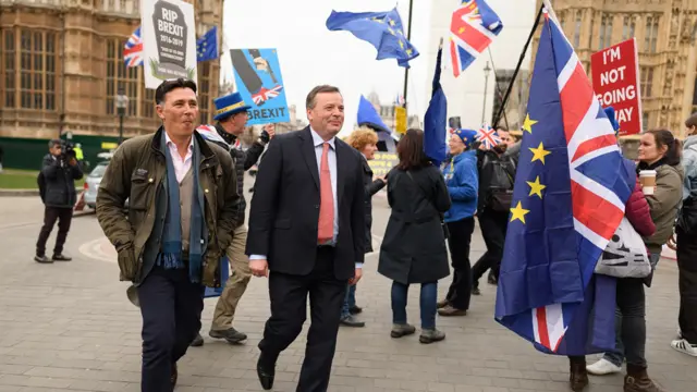 Director of Communications for the Leave.EU campaign Andy Wigmore (L) and businessman and co-founder of the Leave.EU campaign, Arron Banks (C) walk through pro-EU demonstrators outside the Houses of Parliament