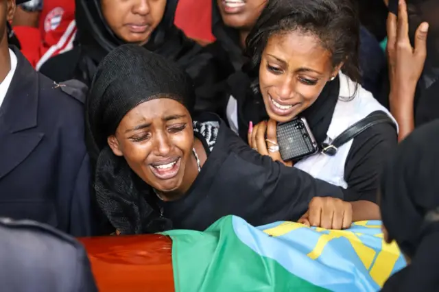 Mourners of victims of the crashed accident of Ethiopian Airlines react beside a coffin during the mass funeral at Holy Trinity Cathedral in Addis Ababa, Ethiopia, on March 17, 2019