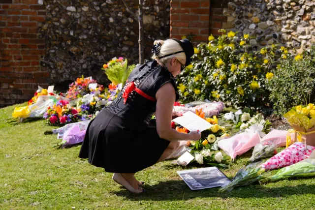 Woman looks at floral tributes.