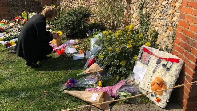 Man looks at floral tributes to Keith Flint in Bocking.