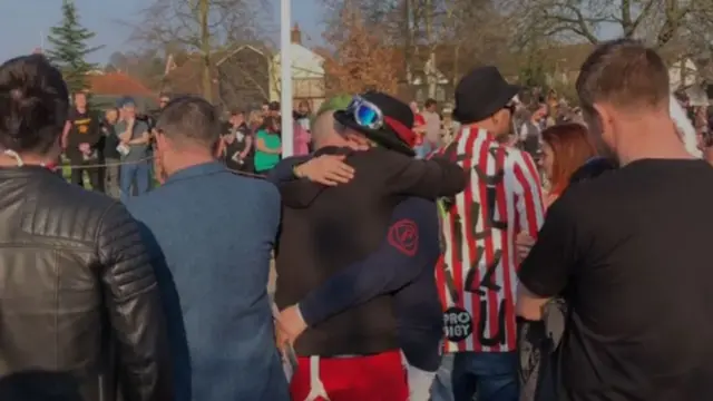 Fans hug outside church.