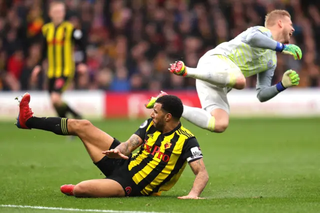 Troy Deeney of Watford tackles Kasper Schmeichel of Leicester City