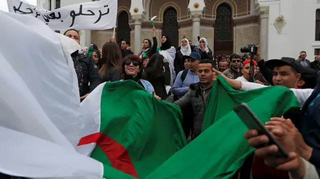 People carry a national flag during a protest against Algeria's President Abdelaziz Bouteflika, in Algiers