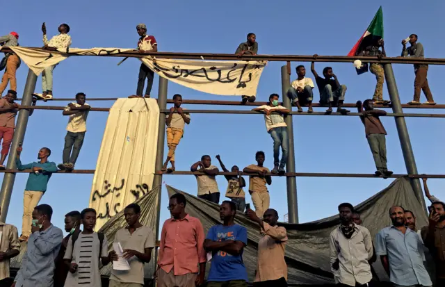 Sudanese demonstrators chant slogans as they stand on a torn billboard during a protest rally demanding Sudanese President Omar Al-Bashir to step down, outside Defence Ministry in Khartoum, Sudan April 9, 2019.