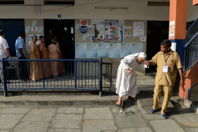 A Catholic nun is assisted as she leaves a polling station after voting during India's general election in Hyderabad on April 11, 2019