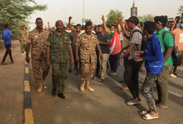 Sudanese protesters cheer passing soldiers in Khartoum