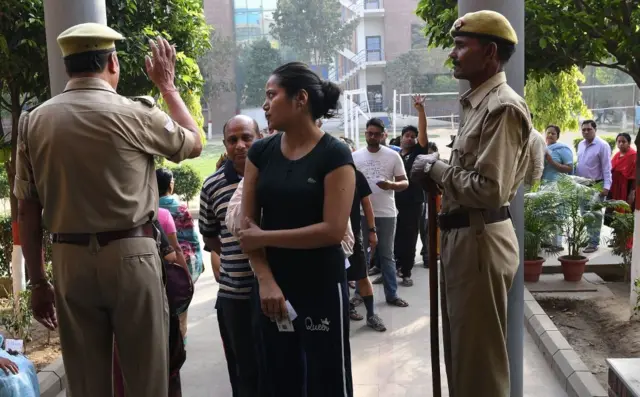 An Indian security officer instructs waiting voters at a polling station in Ghaziabad, Uttar Pradesh