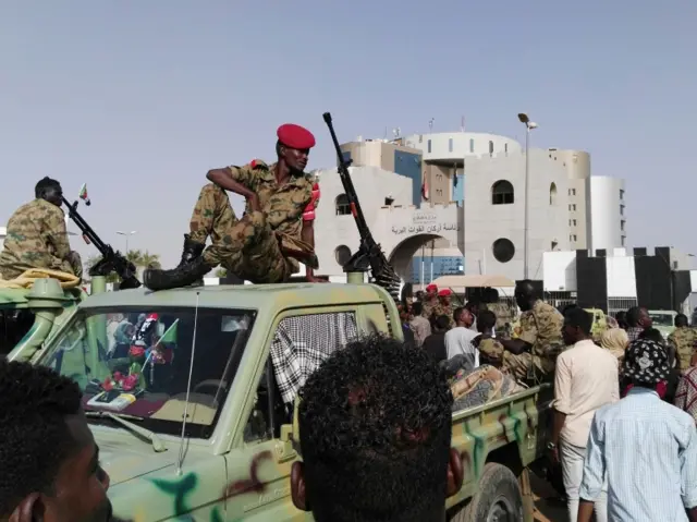 Sudanese soldiers look on as demonstrators gather in a street in central Khartoum on April 11, 2019