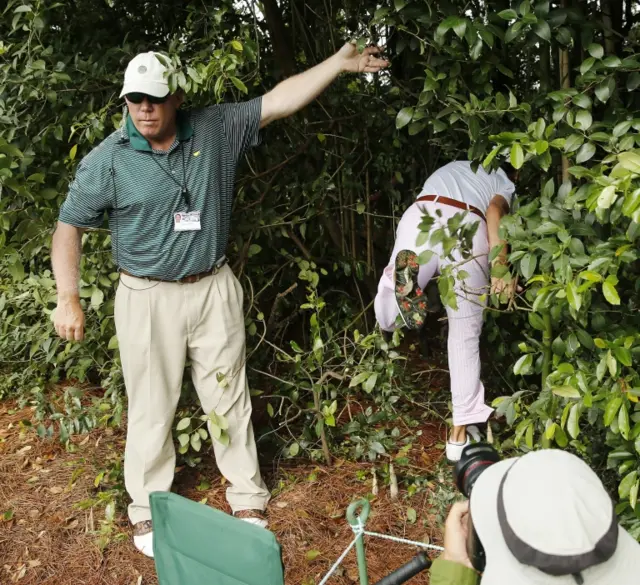 Bill Horschel of the US climbs into the trees along the fourth hole to retreive his unplayable ball