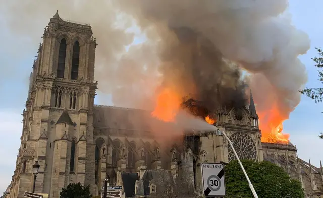 The burning church as water cannons try to extinguish it