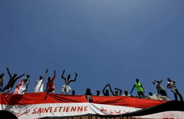 Sudanese demonstrators protest as they stand on a railway bridge near the Defence Ministry in Khartoum