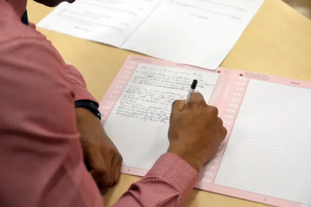 A student writing in an exam paper