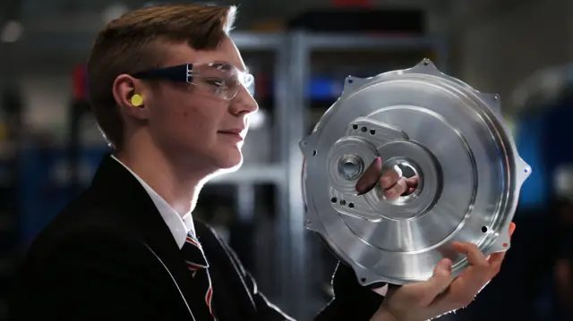 A student looking at a metal wheel