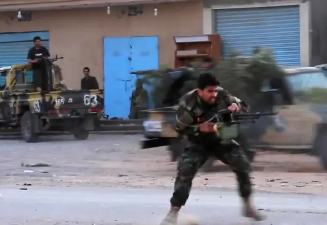 This grab obtained from a video published on the Libyan strongman Khalifa Haftar's self-proclaimed Libyan National Army War Information Division"s Facebook page on April 16, 2019, shows a fighter running while firing a machine gun reportedly in a southern suburb of the capital Tripoli